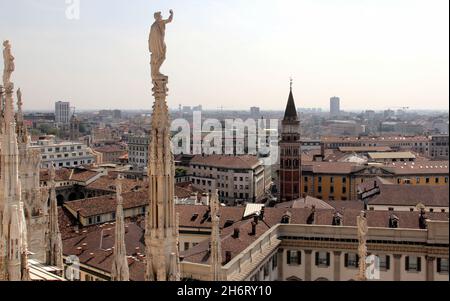 Sculture e guglie del Duomo, dettagli architettonici, skyline della città sullo sfondo, Milano, Italia Foto Stock