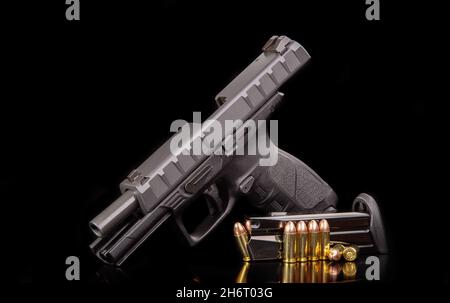 Arma scaricata. Pistola nera moderna e munizioni per esso su una superficie riflettente scuro. Armi corte-barrelate per sport e autodifesa. Armamento f Foto Stock