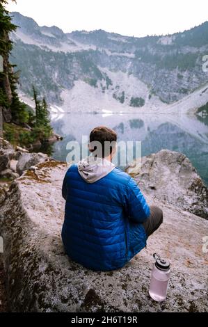 Maschio in giacca blu in puffy presso un lago alpino Foto Stock