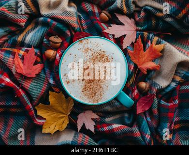 Sopra di latte di spezia di zucca su sciarpa di caduta della plaid con le foglie. Foto Stock