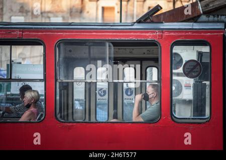 Foto di bianco uomo caucasico a belgrado, serbia, in attesa in un tram per le strade di Belgrado, capitale della Serbia, mentre indossano un respiratore Foto Stock