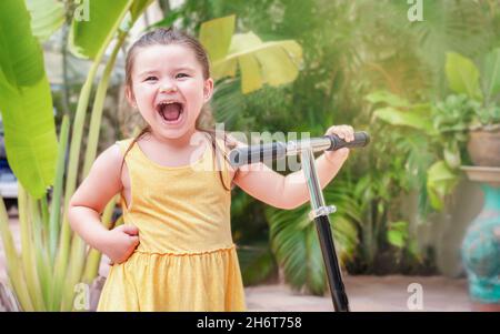 Ritratto del bambino con lo scooter all'aperto su uno sfondo di palme Foto Stock