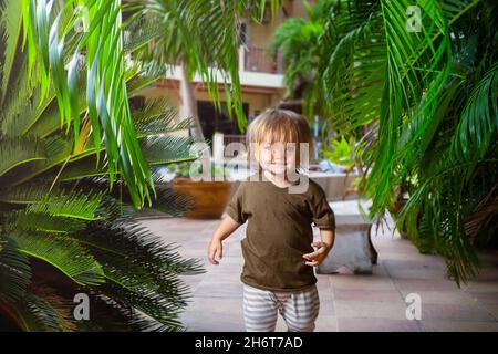 Un bambino corre attraverso le palme in vacanza Foto Stock