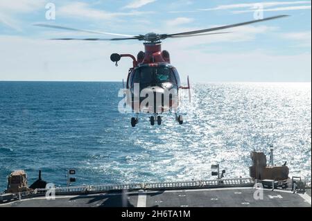 Un equipaggio di elicotteri MH-65 della Guardia Costiera Helicopter Interdiction Tactical Squadron conduce operazioni di volo con i membri dell'equipaggio di USCGC Stone (WMSL 758) al largo della costa della Florida, 14 novembre 2021. Con autorità uniche, un’ampia giurisdizione, capacità operative flessibili e un’ampia rete di partnership nazionali e internazionali, la Guardia Costiera promuove la sicurezza nazionale, la prosperità economica e l’influenza marittima globale. (STATI UNITI Foto della Guardia Costiera di Petty ufficiale 2a classe Shannon Kearney) Foto Stock