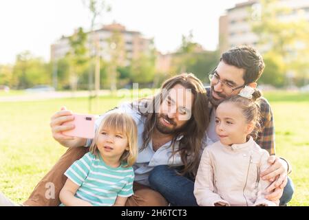 giovane coppia gay maschio con i loro figli che prendono un selfie Foto Stock