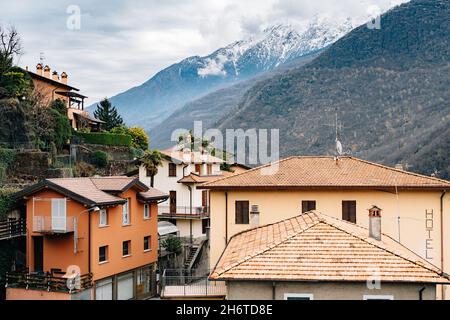 Antiche case con tetti di tegole sullo sfondo delle montagne. Lago di Como, Italia Foto Stock