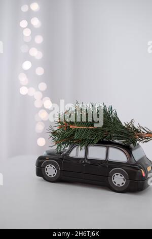 L'automobile di composizione di Natale trasporta un albero di Natale. Su uno sfondo delle luci di festa. Foto di alta qualità Foto Stock