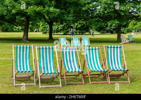 Sedie a sdraio a righe tradizionali nel parco verde. Londra, Inghilterra Foto Stock