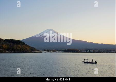 Pescatori su una barca sotto il monte Fuji sul lago Kawaguchiko nella prefettura di Yamanashi al tramonto. Foto Stock