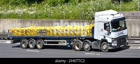 Vista laterale catena di fornitura bianca rimorchio autocarro hgv caricato con grandi sacchi di fibre gialle di materiali da costruzione sfusi sfusi in autostrada UK Foto Stock