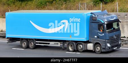 Vista laterale e frontale del camion grigio hgv Truck Blue catena di fornitura Amazon consegna articolata rimorchio driver e logo marchio pubblicità guida su autostrada UK Foto Stock