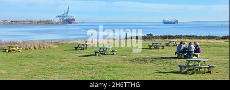I visitatori tavolo da picnic in Essex Wildlife Trust Thameside Nature Reserve & Discovery Park a novembre vista fiume Tamigi Estuary & London Gateway Port UK Foto Stock
