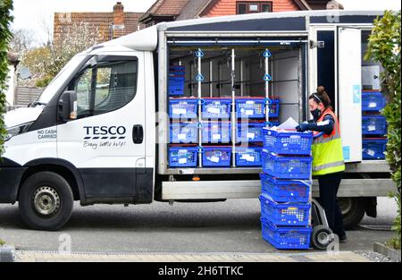 Donna supermercato Tesco shopping online consegna furgone conducente indossando personale ad alta visibilità uniforme scarico ordine cliente fuori casa Inghilterra Regno Unito Foto Stock