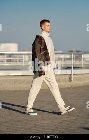 Moda urbana. Giovane uomo in abiti sciolti che cammina per la strada Foto Stock