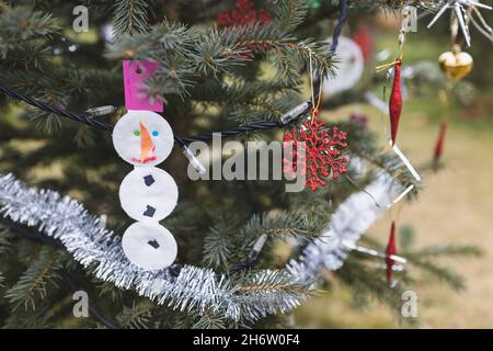 Decorazioni fatte a mano con cialde di cotone cosmetico e carta su albero di Natale all'aperto. Idee creative fai da te per i bambini. Concetto di ambiente. Messa a fuoco selettiva, spazio di copia Foto Stock
