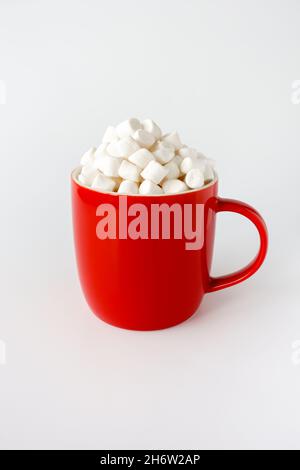 Tazza rossa riempita con mini marshmallows isolato su bianco. Vista ad angolo basso. Foto Stock