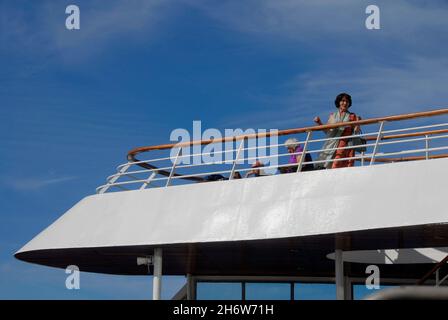 Passeggero femminile su un ponte superiore di una nave da crociera in mare che guarda la vista Foto Stock