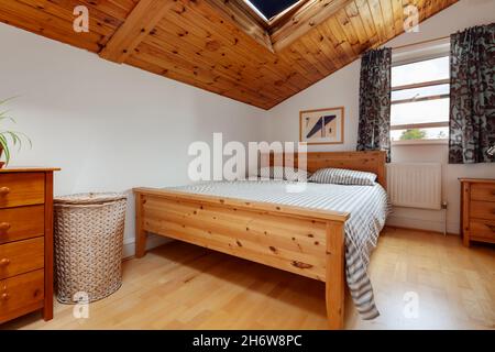 Cambridge, Inghilterra - Agosto 21 2019: Camera da letto mansardata in una casa vittoriana con letto matrimoniale e soffitto in pannelli di legno Foto Stock