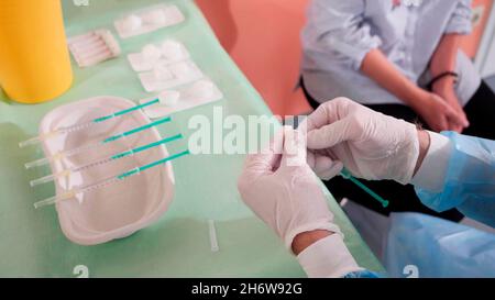 primo piano delle mani di un medico o di un infermiere che prepara un vaccino per vaccinare un paziente, accanto ad esso diversi vaccini preparati sopra la tabella. Foto Stock