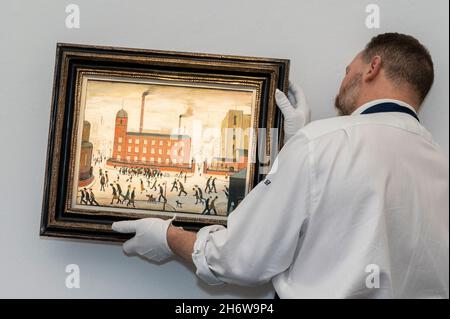 Londra, Regno Unito. 18 novembre 2021. Un tecnico presenta 'Mill Scene', 1959, di Laurence Stephen Lowry (Est.£ 300,000-500,000) in anteprima della prossima vendita di arte moderna britannica e irlandese presso la New Bond Street di Sotheby. Credit: Stephen Chung / Alamy Live News Foto Stock