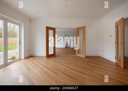 Clavering, Inghilterra - 6 aprile 2020: Grande sala da pranzo in casa nuova di zecca con pareti dipinte di bianco, pavimento in legno e porte a doppia apertura Foto Stock