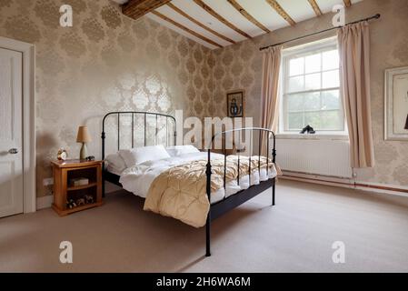 Wimbish, Inghilterra - Luglio 30 2019: Camera da letto in casa d'epoca inglese con arredamento tradizionale e travi a vista inondate di luce da una grande finestra. Foto Stock