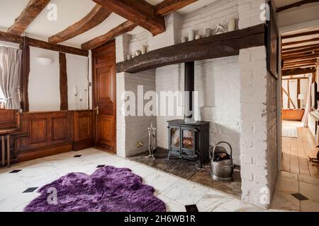 Essex, Inghilterra - Gennaio 18 2019: Caminetto a linglenook con stufa a legna in ghisa in una tradizionale casa britannica con travi a vista Foto Stock