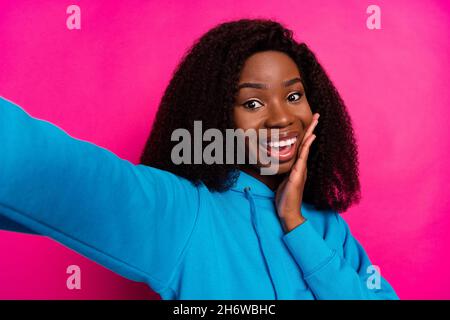 Foto ritratto di donna in abiti blu stupito toccare guancia prendendo selfie sorridente isolato su sfondo di colore rosa brillante Foto Stock