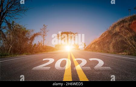 2022 scritto sulla strada statale. Strada asfaltata vuota e bellissimo sfondo cielo alba. Concetto di obiettivo e sfida per la visione del nuovo anno 2022. Foto Stock