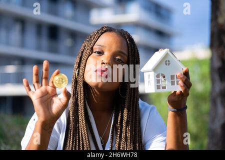 Giovane ragazza latina in posa con una moneta bitcoin e un concetto di investitore casa.Young in miniatura. Foto Stock