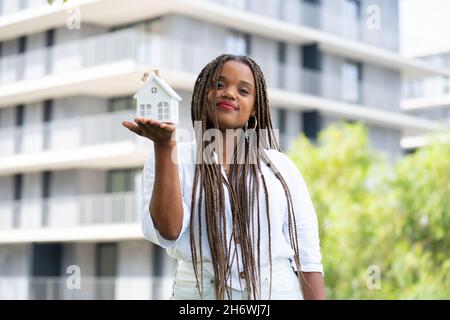 Giovane Latina in posa con una casa in miniatura. Concetto di compratore domestico giovane. Foto Stock