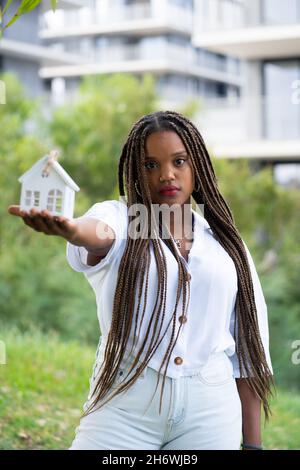 Giovane Latina in posa con una casa in miniatura. Concetto di compratore domestico giovane. Foto Stock