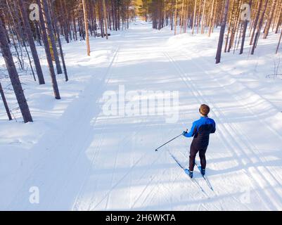 L'atleta uomo allena lo sci di fondo in inverno su una pista coperta di neve nella foresta. Foto Stock