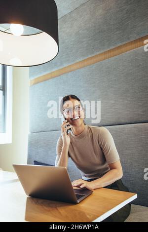 Buon professionista di affari che prende una chiamata. Giovane donna d'affari allegra sorridente mentre comunica con i suoi partner commerciali. Giovane femmina ent Foto Stock