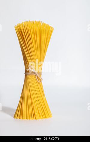 Un mazzo verticale, un mazzo di spaghetti crudi legati con corda. Fascio su sfondo bianco. Cucina italiana. Foto Stock