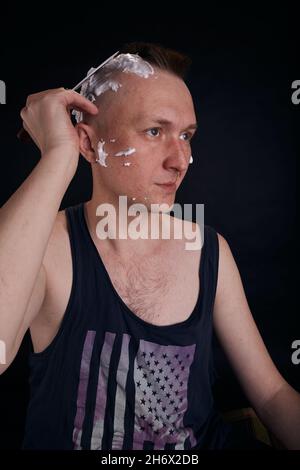 Uomo che fa i capelli da sé a casa mentre Covid-19 . Stile di vita auto-scoppio. Foto Stock