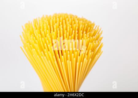 Un mazzo verticale, un mazzo di spaghetti crudi legati con corda. Fascio su sfondo bianco. Cucina italiana. Foto Stock