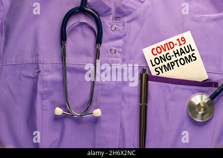 COVID-19 simbolo dei sintomi del codice a lunga distanza. Carta bianca con parole Covid-19 sintomi a lunga distanza. Uniforme medica, penna metallica e stetoscopio. Medico, CO Foto Stock