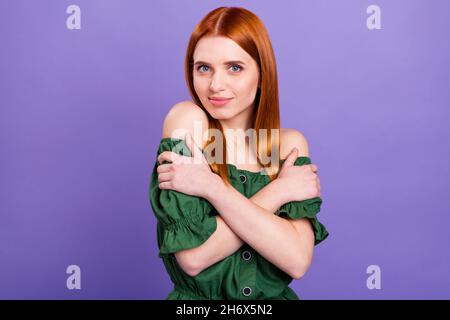 Foto di bella adorabile giovane donna indossare blusa verde sorridente abbracciandosi isolato viola sfondo colore Foto Stock