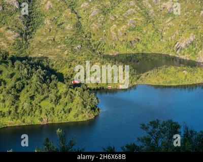 Cabina rossa solitaria al lago vicino mt. Sukkkertoppen, la montagna vicino a Hamn i Senja, Senaj isola, Norvegia Foto Stock