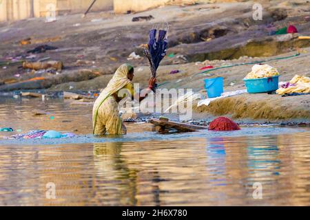 VARANASI, UTTAR-PRADESH/INDIA - 23 maggio 2012: Le donne lavano i loro sari e vestiti nel fiume santo di Ganga Foto Stock