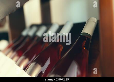 Bottiglie di vino di rosa impilate su una rastrelliera di legno. Foto Stock