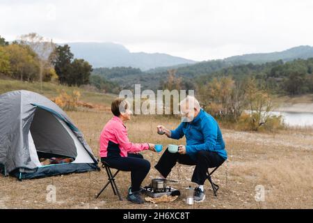 Senior coppia mangiare e campeggio dopo una giornata di trekking al lago - Focus sul viso donna Foto Stock