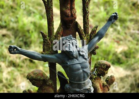 La statua di Gesù è cablata su una recinzione arrugginita del cimitero nel nord della Francia. Foto Stock