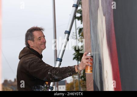 16 novembre 2021, Cheltenham, Inghilterra, High Street Car Park. L'artista Andy 'dice' Davies dipinge un murale a sorpresa per il cantante Jaz Coleman, della band punk degli anni '80 che uccide Joke. Foto Stock