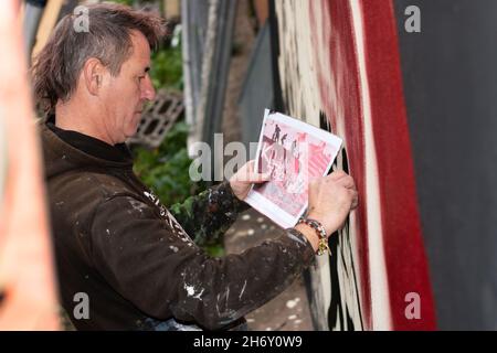 16 novembre 2021, Cheltenham, Inghilterra, High Street Car Park. L'artista Andy 'dice' Davies dipinge un murale a sorpresa per il cantante Jaz Coleman, della band punk degli anni '80 che uccide Joke. Foto Stock