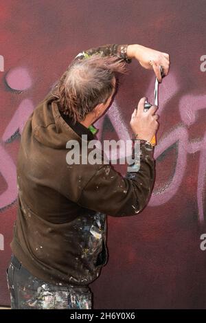 16 novembre 2021, Cheltenham, Inghilterra, High Street Car Park. L'artista Andy 'dice' Davies dipinge un murale a sorpresa per il cantante Jaz Coleman, della band punk degli anni '80 che uccide Joke. Foto Stock