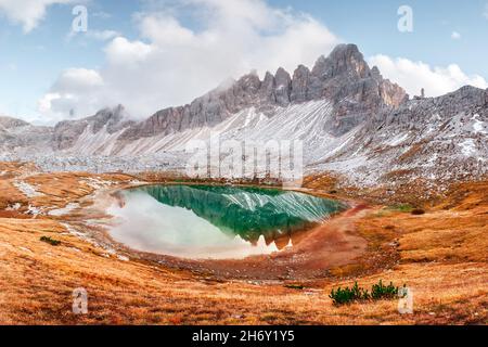 Acque cristalline del lago di Piani nel Parco Nazionale delle tre Cime di Laveredo, Dolomiti, Italia. Paesaggio pittoresco con montagne innevate, erba d'arancio e laghetto in autunno delle Alpi dolomitiche Foto Stock