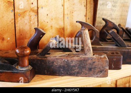 Primo piano di una fila di antichi aerei da falegname, su una mensola in legno. Foto Stock