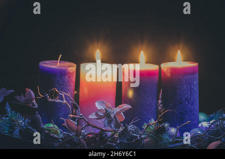 candele rosa e viola nella decorazione della corona dell'avvento su sfondo nero Foto Stock